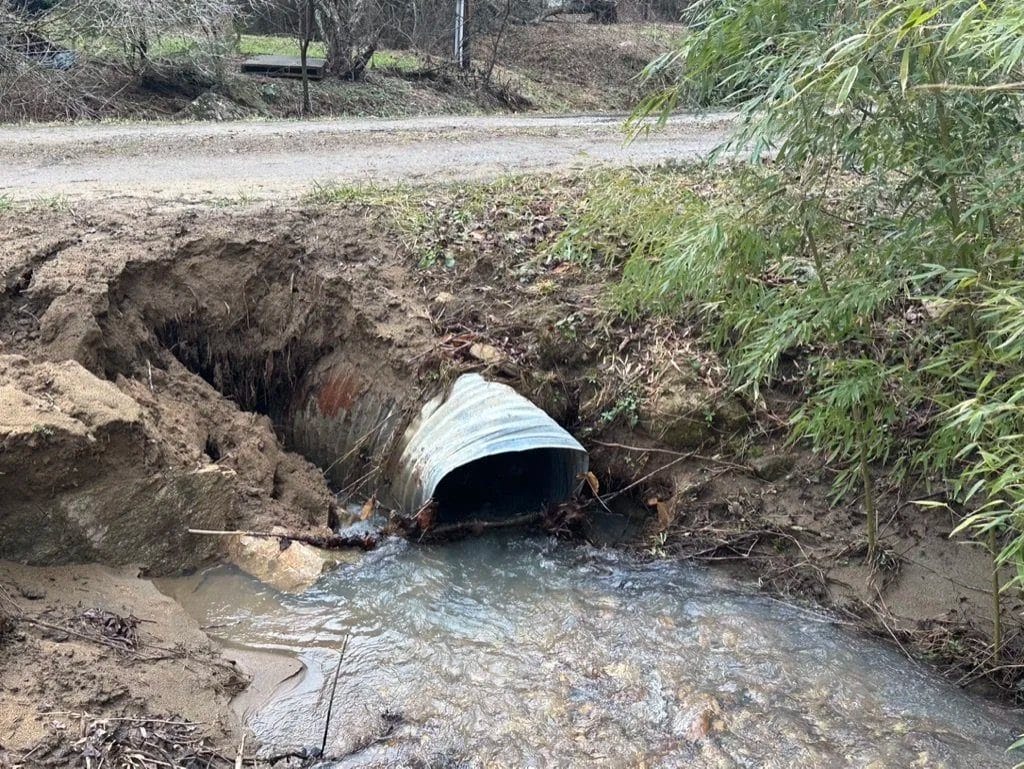 Culvert pipe washed out by floodwater under a gravel road