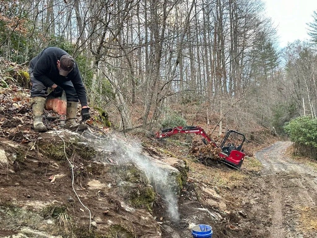 Crew member working on a broken water line on a wooded hillside