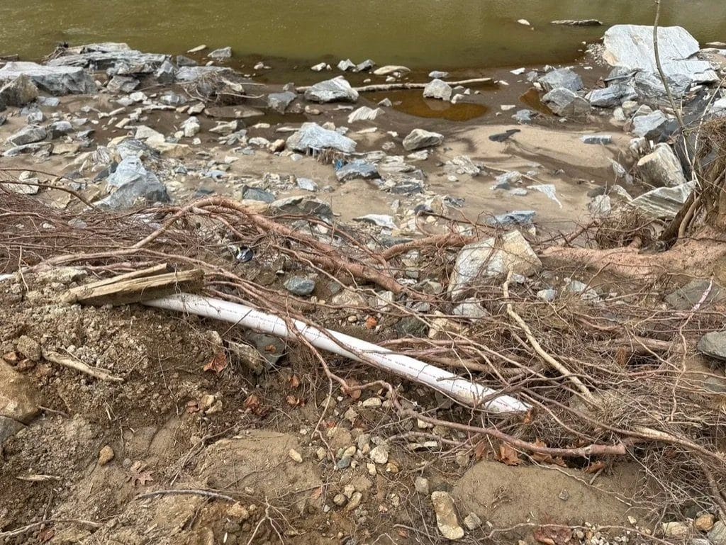 Washed rock, roots and a displaced pipe beside a creek