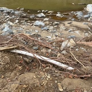Pipe exposed in storm debris near a creek